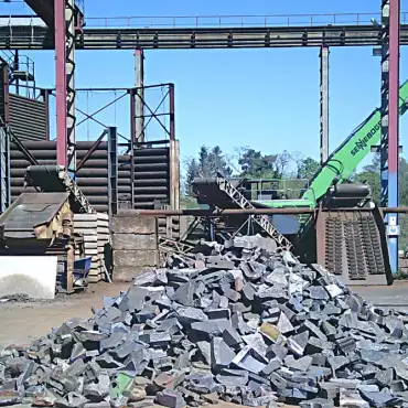 Ein Haufen Metallschrott liegt vor einer Maschine in einer industriellen Umgebung.