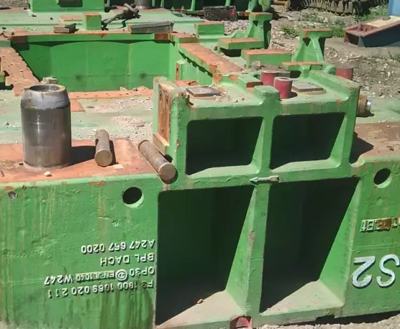 Grüne Bauteile von Industrieanlagen liegen auf dem Boden.