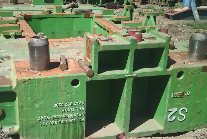 Grüne Bauteile von Industrieanlagen liegen auf dem Boden.