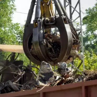 Ein großer Kran hebt einen großen Metallhaufen auf einer Baustelle an.