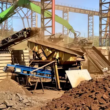Eine große Maschine bearbeitet einen Haufen Schrottmetall auf einer Baustelle.
