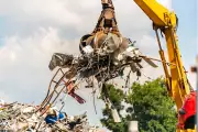 Ein Kran transportiert eine große Menge Metall und Schrott in der Luft.