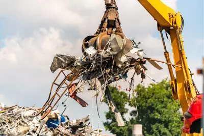 Ein Kran transportiert eine große Menge Metall und Schrott in der Luft.
